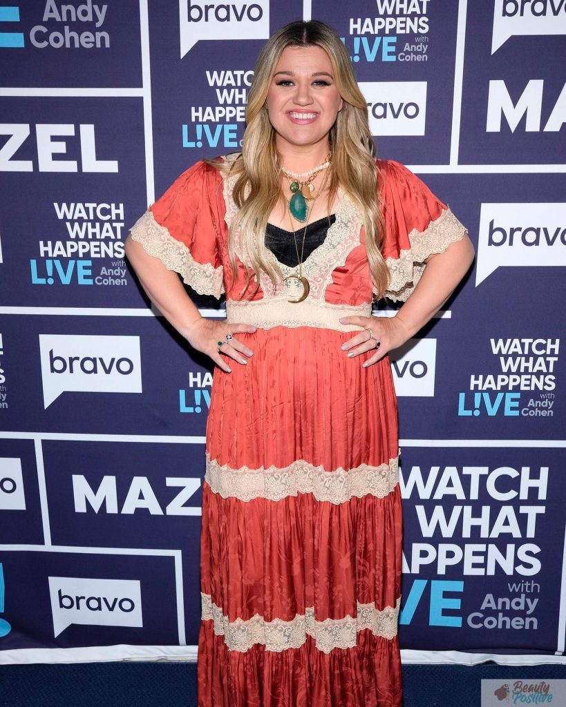 Kelly Clarkson in a coral dress with lace trim on the Watch What Happens Live set