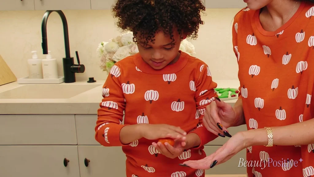Stormi Webster pressing cookie dough, her natural curls loose